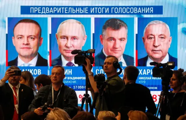 Journalists stand in front of the screen with preliminary results of the presidential elections during a briefing at the Central Election Commission in Moscow