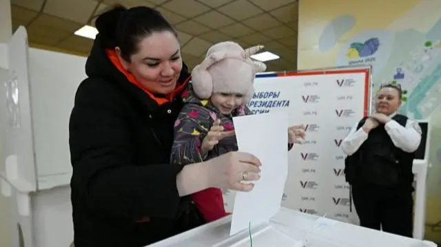 A woman votes with a child in Russia's presidential election at a polling station in Moscow on 17 March 17 2024