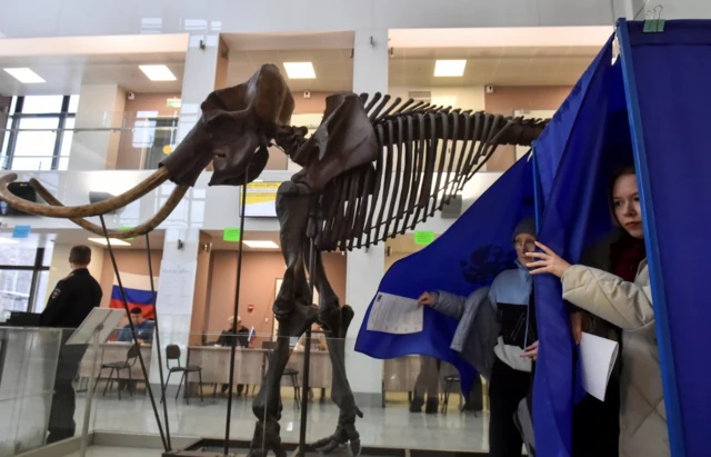 Booths are set near a giant mammoth skeleton at a polling station located in Novosibirsk State University in Novosibirsk, Russia - 17 March 2024