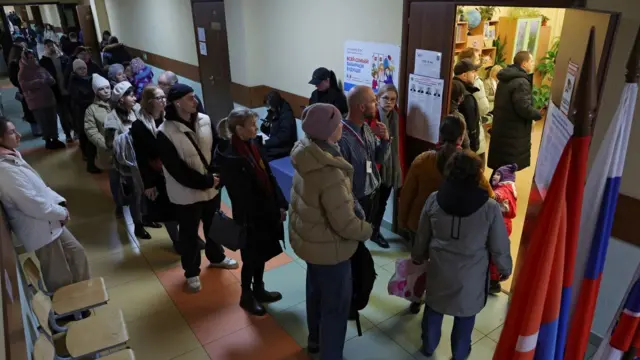 Voters stand in line at a polling station in the town of Kudrovo in the Leningrad region of Russia