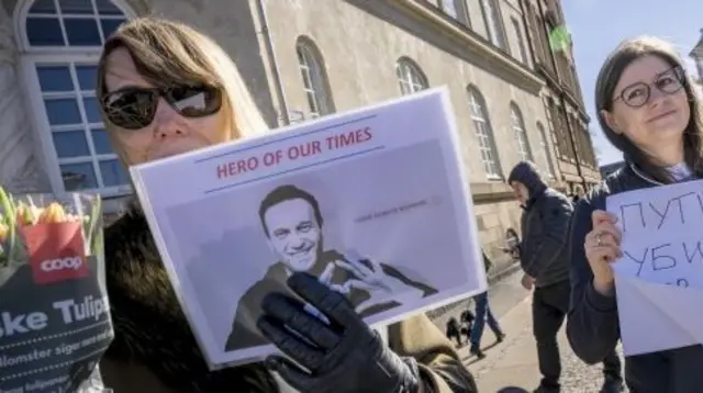 A woman holds a placard with a picture of Navalny as people waited to vote at the Russian embassy in Copenhagen on 17 March