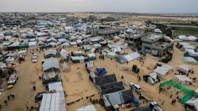 A bird's-eye view of a tent city set up on sandy ground