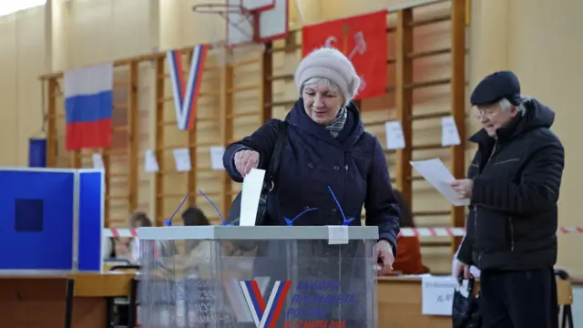 A voter casts a ballot at a polling station on the final day of the presidential election in Saint Petersburg, Russia