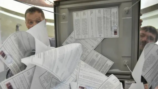 Members of an electoral commission empty a ballot box to count votes