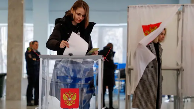 A Russian woman casts her ballot during the presidential elections at a polling station in Moscow, Russia