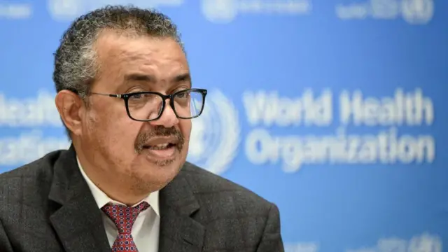 Up close shot of Tedros Adhanom Ghebreyesus in front of a blue banner with 'World Health Organization' written on it in white text