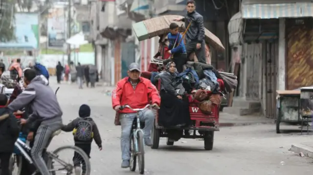 Palestinian residents leave the area with a few items after the Israeli army forces besiege the Al-Shifa hospital with tanks and heavy gunfire in Gaza City, Gaza on March 18, 2024