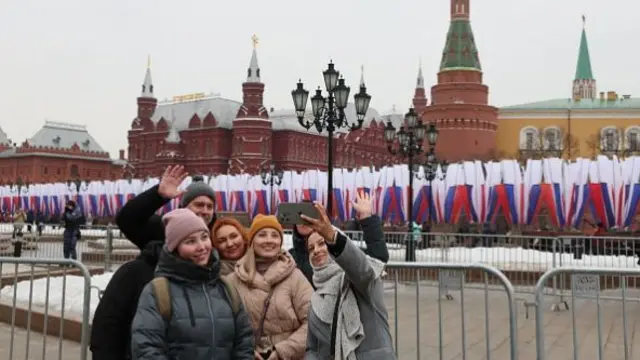 People pose for a selfie picture with the Kremlin