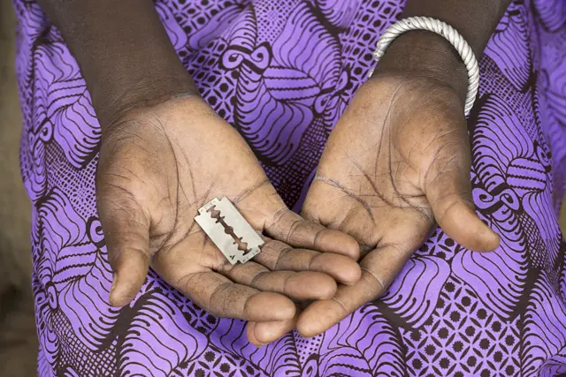 A woman holds a razor blade in Burkina Faso