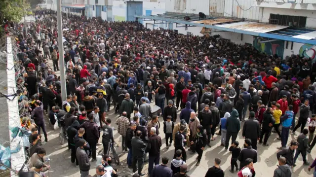 An enormous crowd in front of a dilapidated building