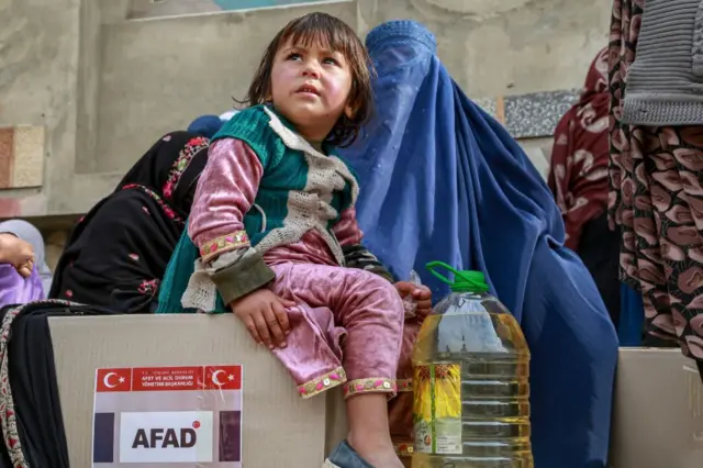 A child sits on a box of food donated by Turkey