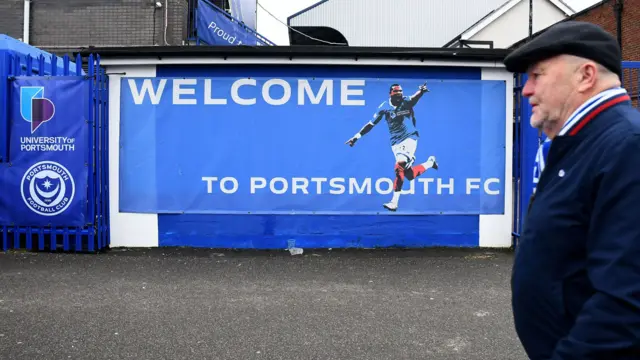 A fan walks towards the entrance of Fratton Park, home of Portsmouth