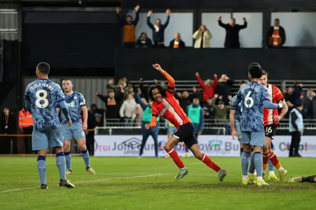 Chong raises a fist to the sky to celebrate pulling a goal back for Luton.