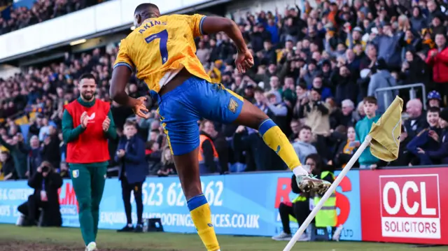 Lucas Akins kicks the corner flag in celebration after scoring for Mansfield