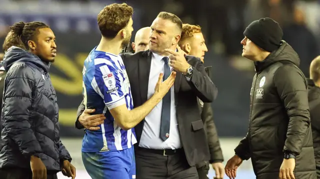 Bolton manager Ian Evatt (centre right) exchanges words with Wigan Athletic's Charlie Goode at the end of the game between the two sides