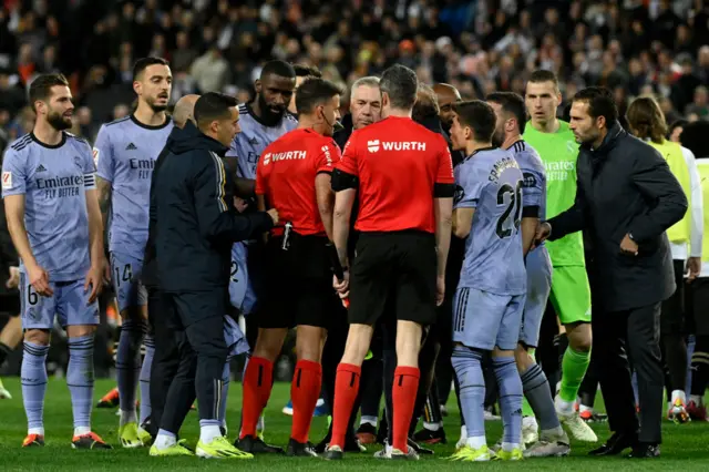 Referee surrounded by Real Madrid players and staff