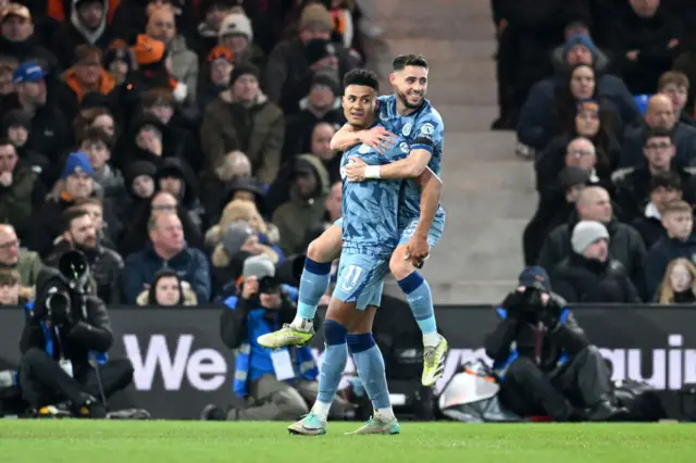 Watkins carries Moreno to the corner during his goal celebration.