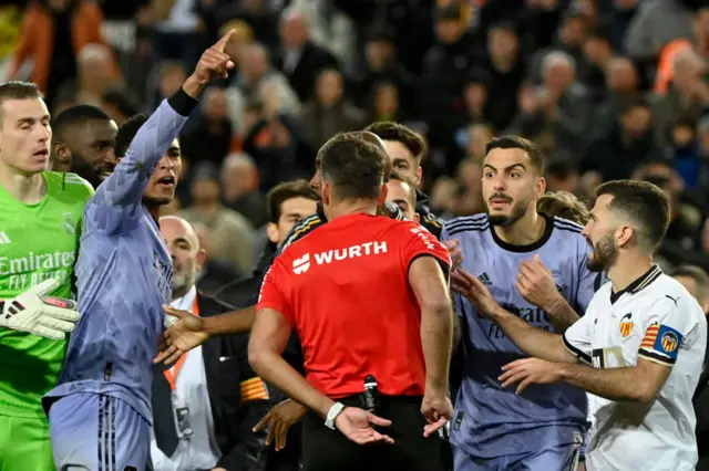 Referee surrounded by Real Madrid players