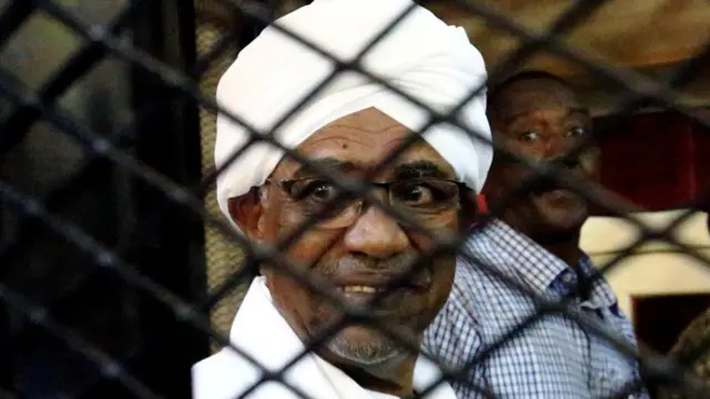 Sudan's former president Omar Hassan al-Bashir smiles as he is seen inside a cage at the courthouse where he is facing corruption charges, in Khartoum, Sudan August 31, 2019