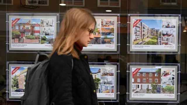 A pedestrian passes a real estate agency in London, Britain, 01 December 2022.