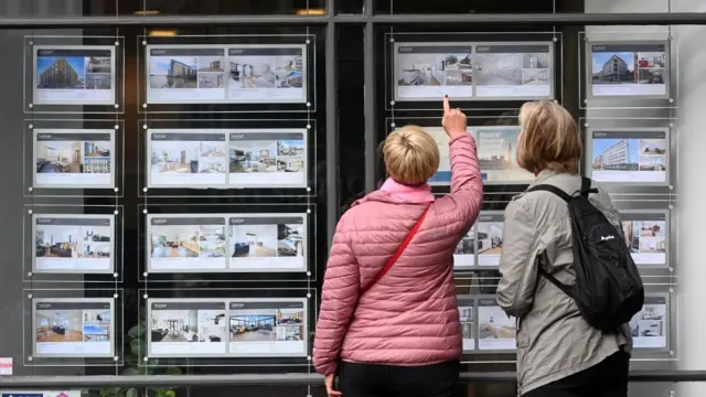 People look over sales options at a real estate agent in London