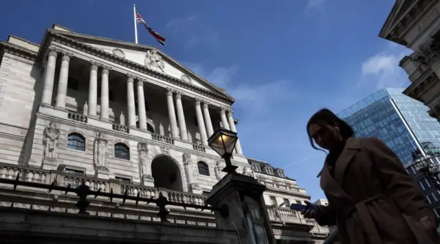 A pedestrian passes the Bank of England in London, Britain, 21 March 2024.