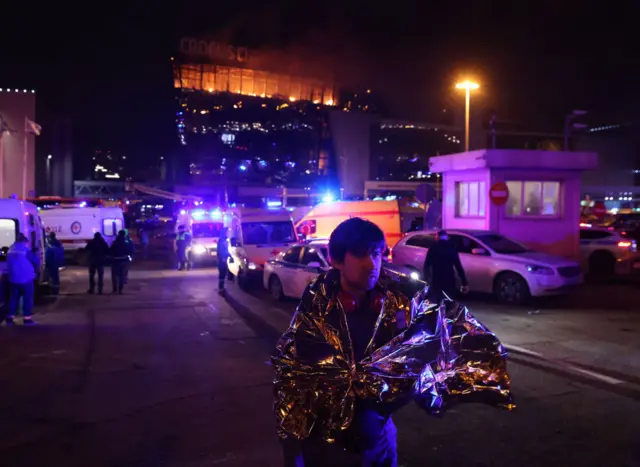 A man wrapped in a heat blanket outside the concert hall