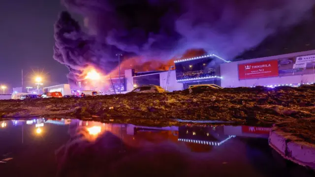 Smoke from fire rises above the burning Crocus City Hall concert venue following a shooting incident, outside Moscow, Russia.