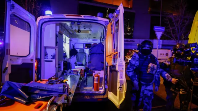 Russian law enforcement officers stand guard near the burning Crocus City Hall concert venue following a shooting incident, outside Moscow, Russia.