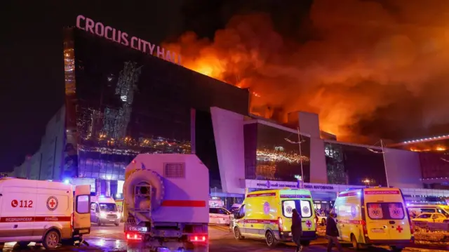 Vehicles of Russian emergency services are parked near the burning Crocus City Hall concert venue following a reported shooting incident, outside Moscow, Russia, March 22, 2024.