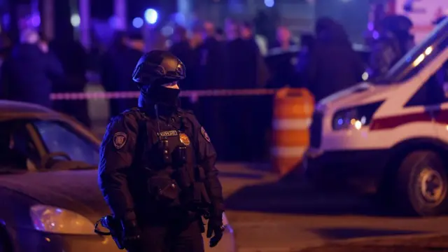 A Russian law enforcement officer stands guard near the burning Crocus City Hall concert venue following a reported shooting incident, outside Moscow, Russia, March 22, 2024.