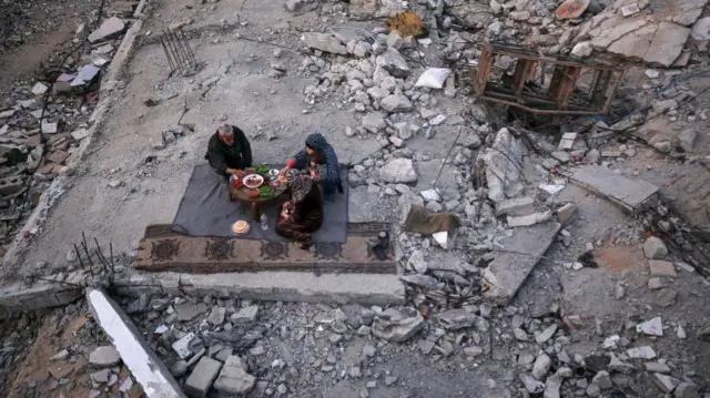 Khaled Naji and family share a meal in the ruins of his home in Gaza