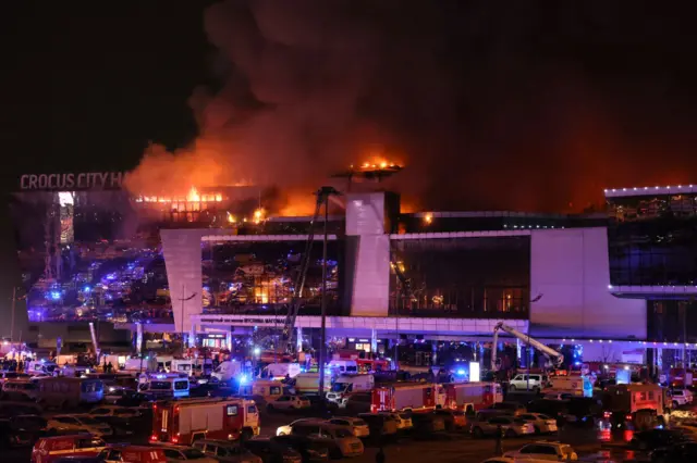 Emergency services vehicles are seen outside the burning Crocus City Hall concert hall following the shooting incident outside Moscow, on March 22, 2024.