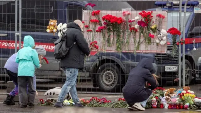 People bring flowers to the burned Crocus City Hall concert venue following a terrorist attack in Krasnogorsk, outside Moscow, Russia, 23 March 2024.