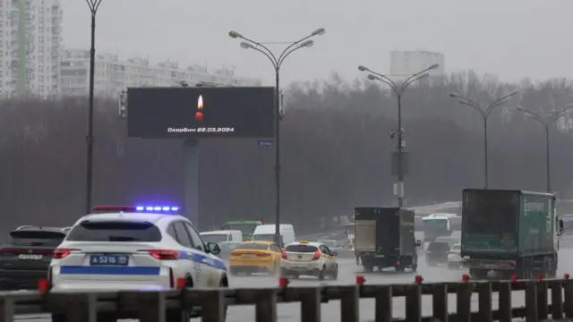 An advertising screen displays a lit candle image and a slogan "Mourn" written in the Russian langauge.