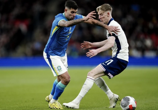 Brazil's Bruno Guimaraes (left) and England's Anthony Gordon battle for the ball