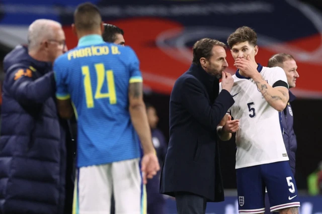 England manager Gareth Southgate speaks with England's John Stones as Brazil coach Dorival Junior speaks with Brazil's Fabricio Bruno