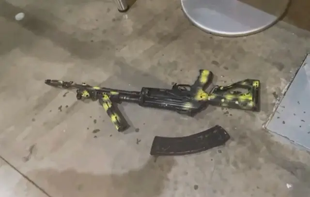 A Kalashnikov assault rifle lies on the ground as Russian investigators work inside Crocus City Hall concert venue - 23 March 2024