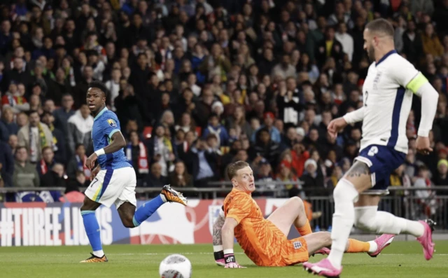 Brazil's Vinicius Junior shoots past England's Jordan Pickford before Kyle Walker intercepts the ball