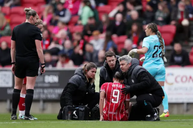 Hayles receives treatment for a shoulder injury while sat on the floor