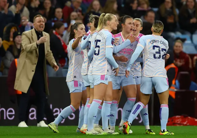 Arsenal players celebrate as Eidevall claps in the background