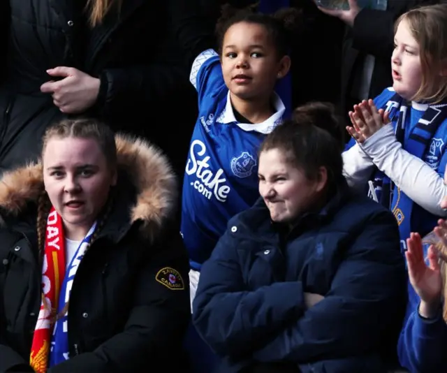 A fan stands with her arms crossed and a glum expression on her face