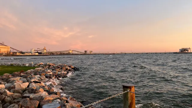 A view from the shoreline - a bridge in the distance slopes into the water