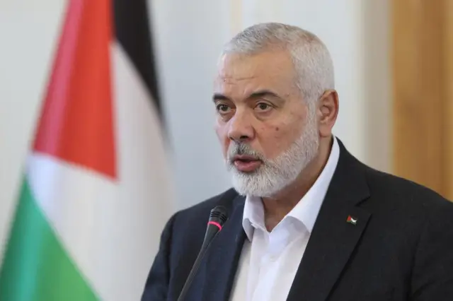 Hamas leader Ismail Haniyeh is pictured speaking into a microphone at a press conference in Tehran, Iran, with a Palestinian flag positioned behind him.