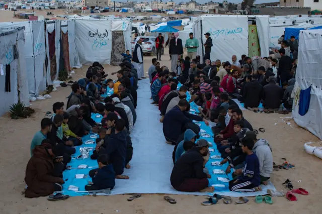 People kneeling in lines waiting to eat