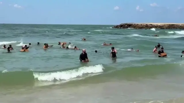 People collect aid airdropped in the sea in northern Gaza (25 March 2024)