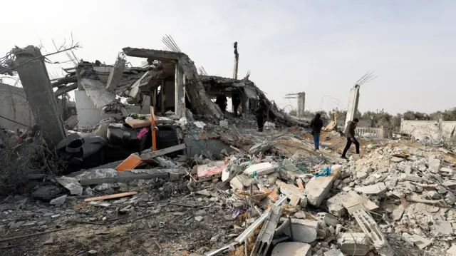 Palestinians inspect the site of an Israeli strike on a house in Rafah, in the southern Gaza Strip (26 March 2024)