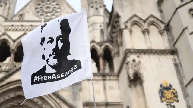 A flag depicting Julian Assange flutters outside the entrance to the Royal Courts of Justice