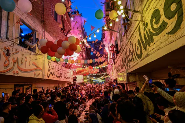 People sitting down to a mass iftar meal in the street.