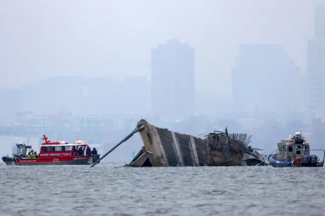 A large section of the bridge lies partially submerged in the river